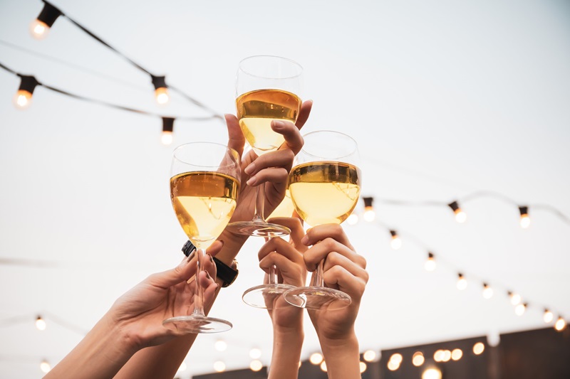 Group of people in party and celebrating together with white wine. Happy Asian people enjoy partying in festival and celebrate with white wine on the roof top bar and restaurant of 5 stars hotel.